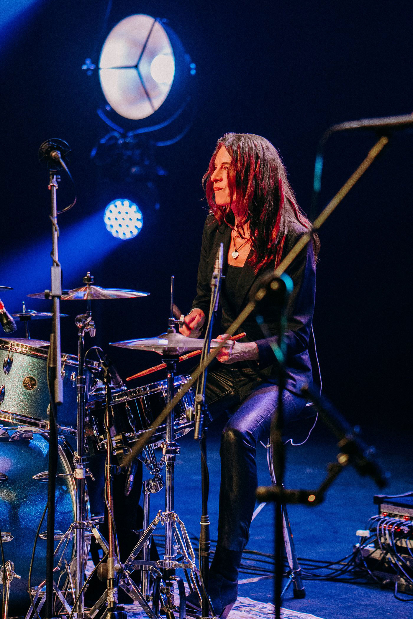 Gail James seated at her drum kit under blue stage lighting