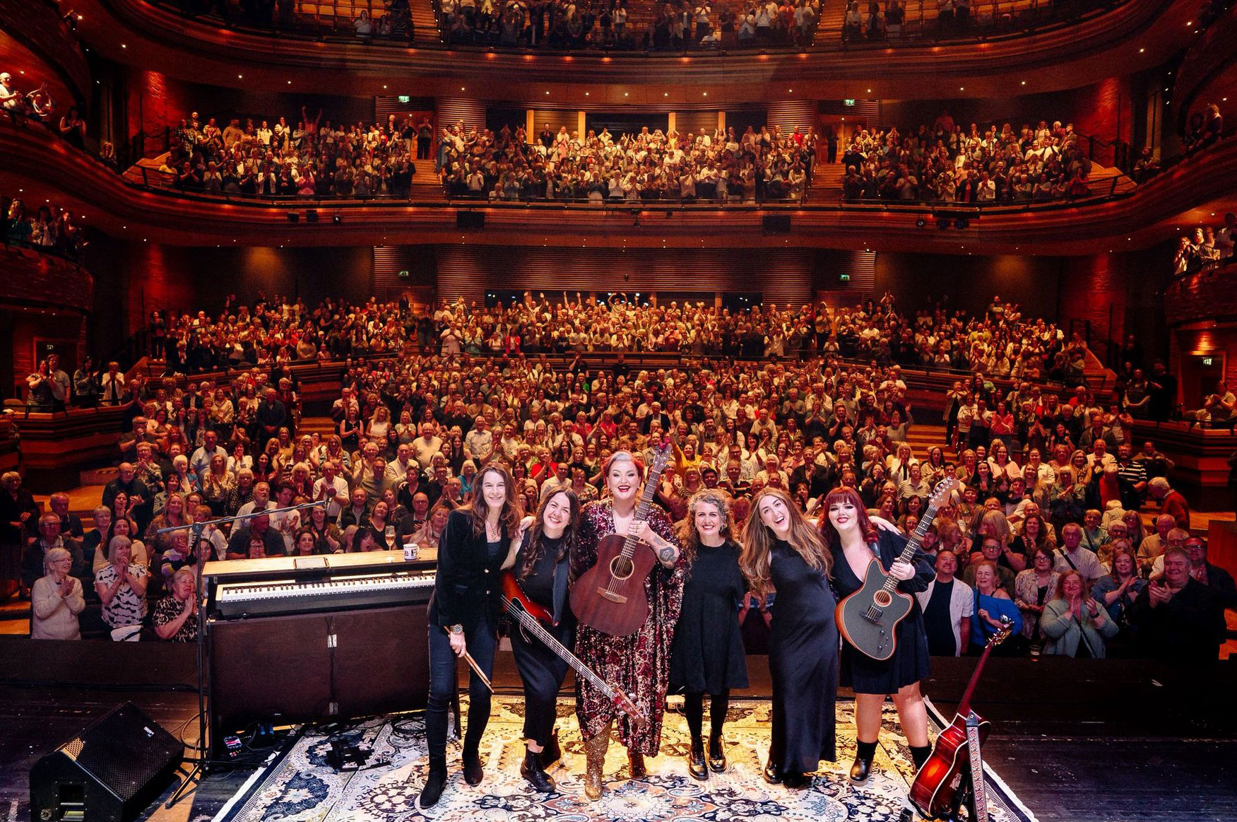 Gail James and band taking a curtain call on stage before a full theatre audience